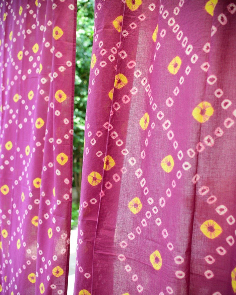 Purple and yellow bandhani fabric with foliage in the background