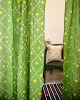 Green and Yellow bandhani or tie dye curtains with a rug and chair in the background