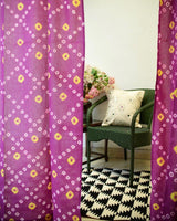 Purple and Yellow bandhani or tie dye curtains with a rug and chair in the background